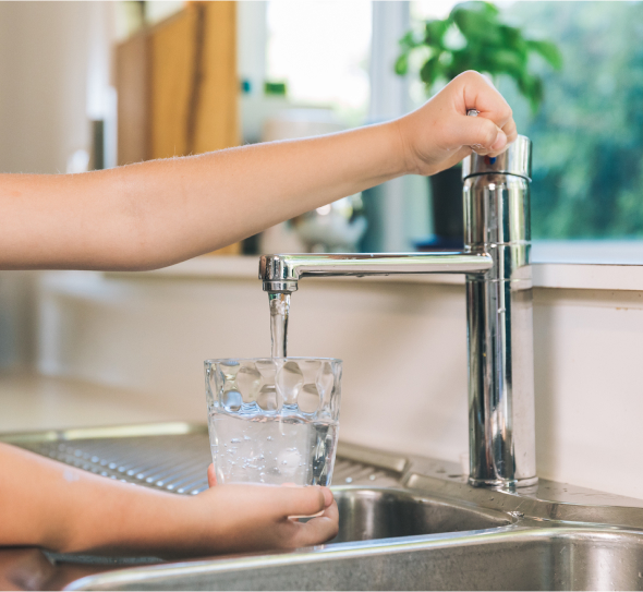 Girl pouring glass of water from the tap
